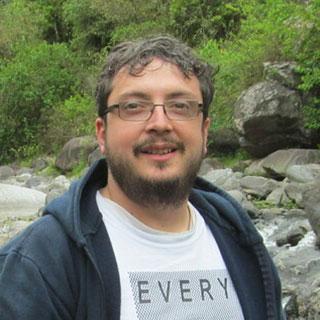 Headshot photo of man standing near a river